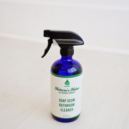 A photo of a 16 fl oz cobalt blue spray bottle with Nature's Notes Soap Scum Bathroom Cleaner.