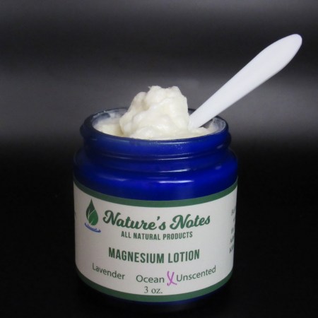 Cobalt blue jar with white magnesium lotion on a spatula.