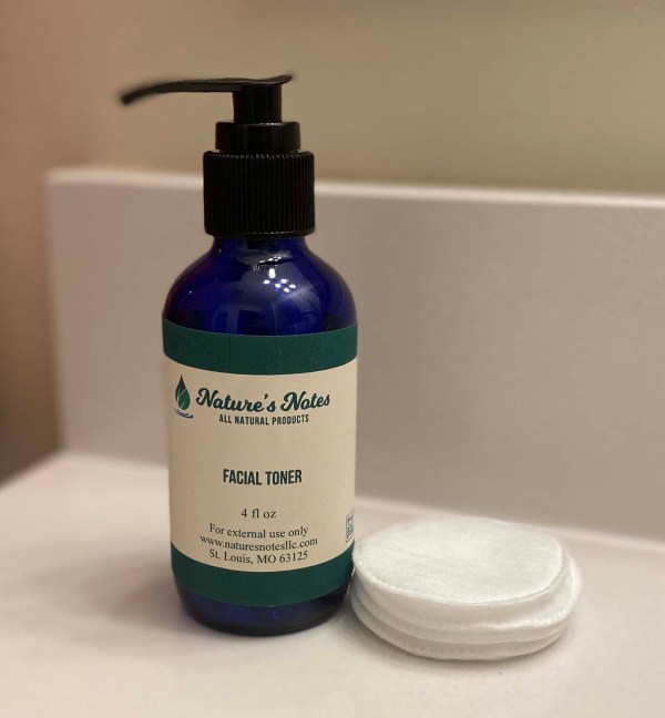 Cobalt blue 4 oz pump bottle with all-natural face toner. Depicted with a stack of cotton rounds.