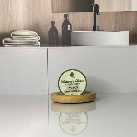 A photo of a 3oz bar of glycerin soap with loofah inside sitting on a bamboo soap tray.